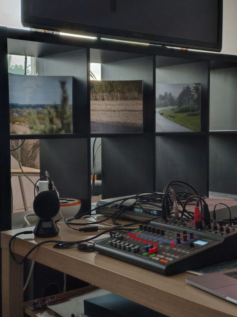 Close-up of a workshop table featuring a Zoom H3-VR ambisonic recorder and LiveTrak L-8 mixer, with High Pressure project photographs in the background